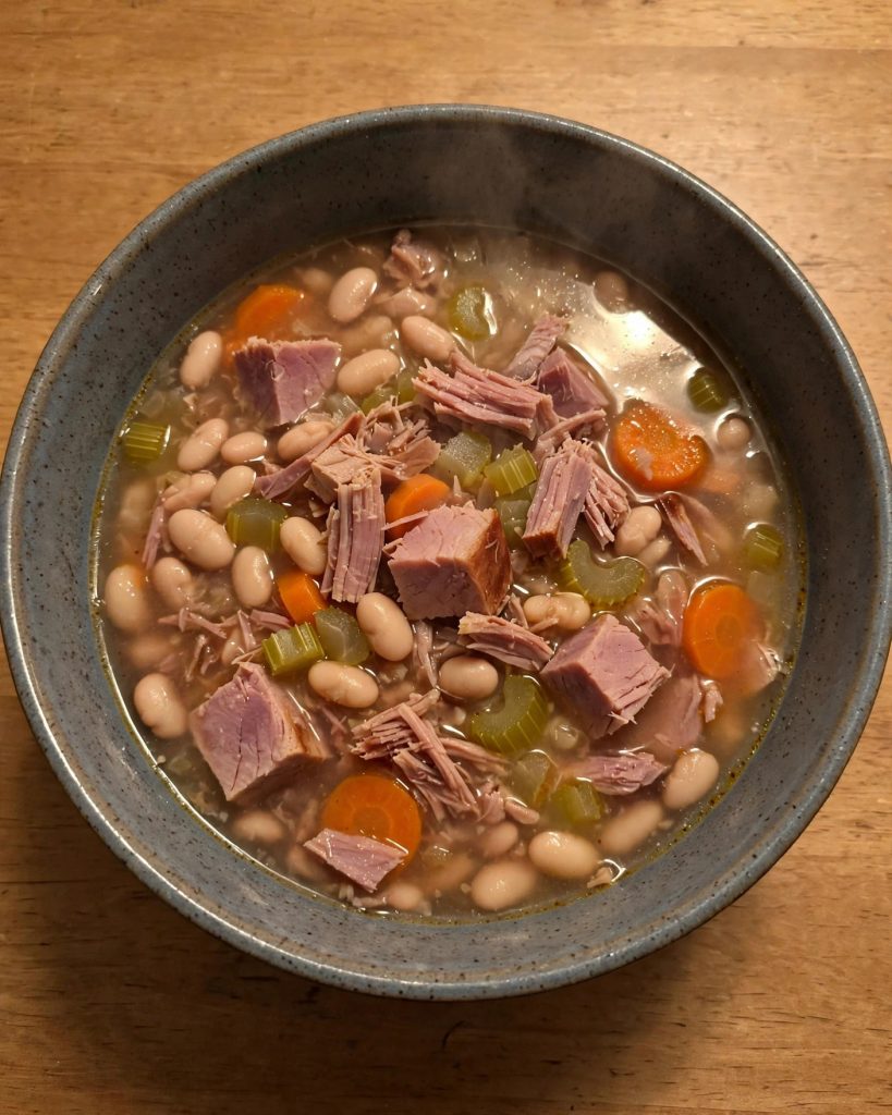 A bowl of ham and bean soup with tender navy beans and chunks of ham