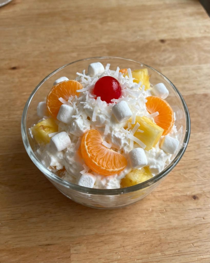 A serving of ambrosia salad in a small glass dessert bowl