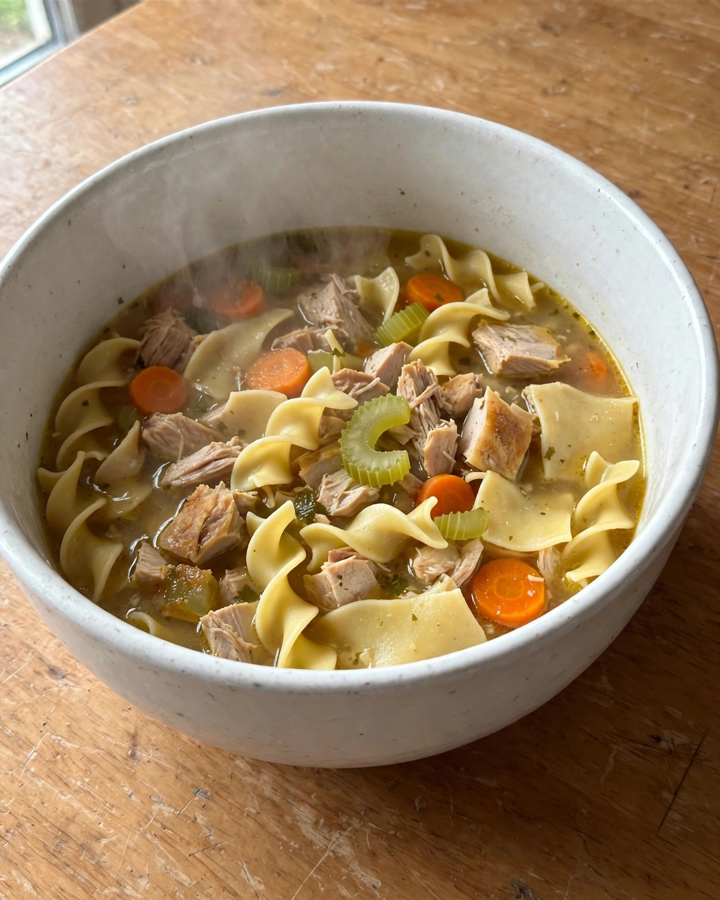 A big bowl of leftover turkey noodle soup with egg noodles and carrots