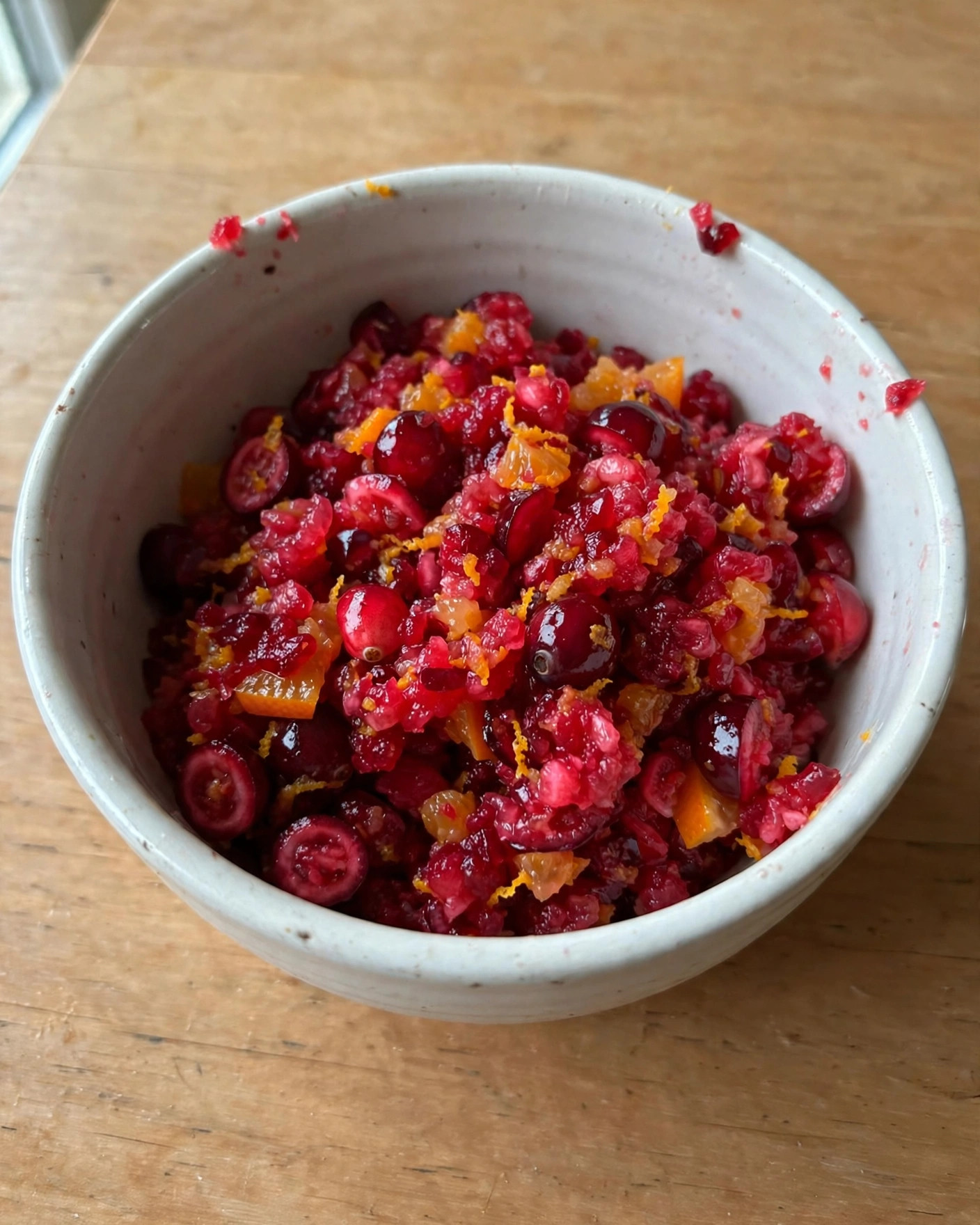 Fresh cranberry orange relish in a white bowl on a wooden table